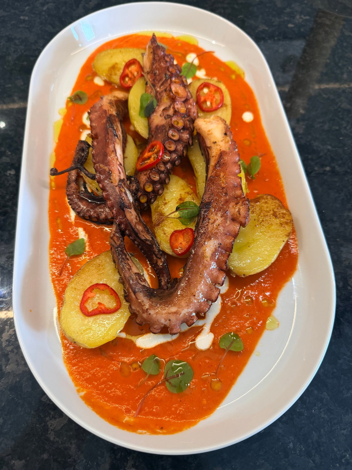 Grilled octopus with potatoes, red pepper sauce and fresh chilli